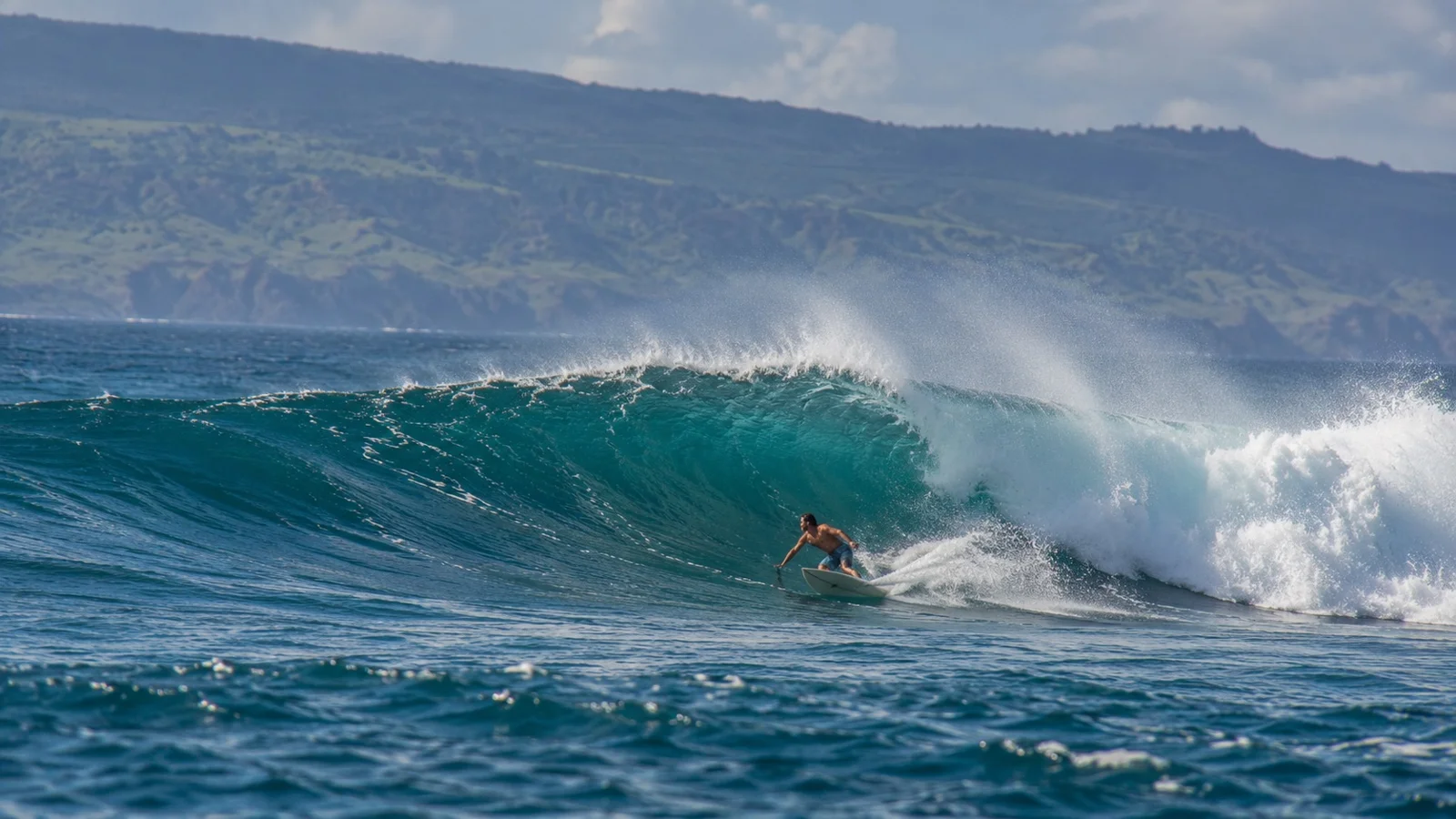 A surfer riding a curling wave at Honolua